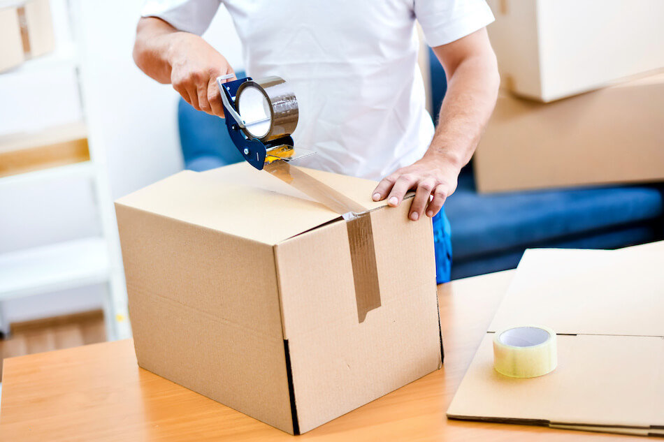 Person sealing and labeling a moving box