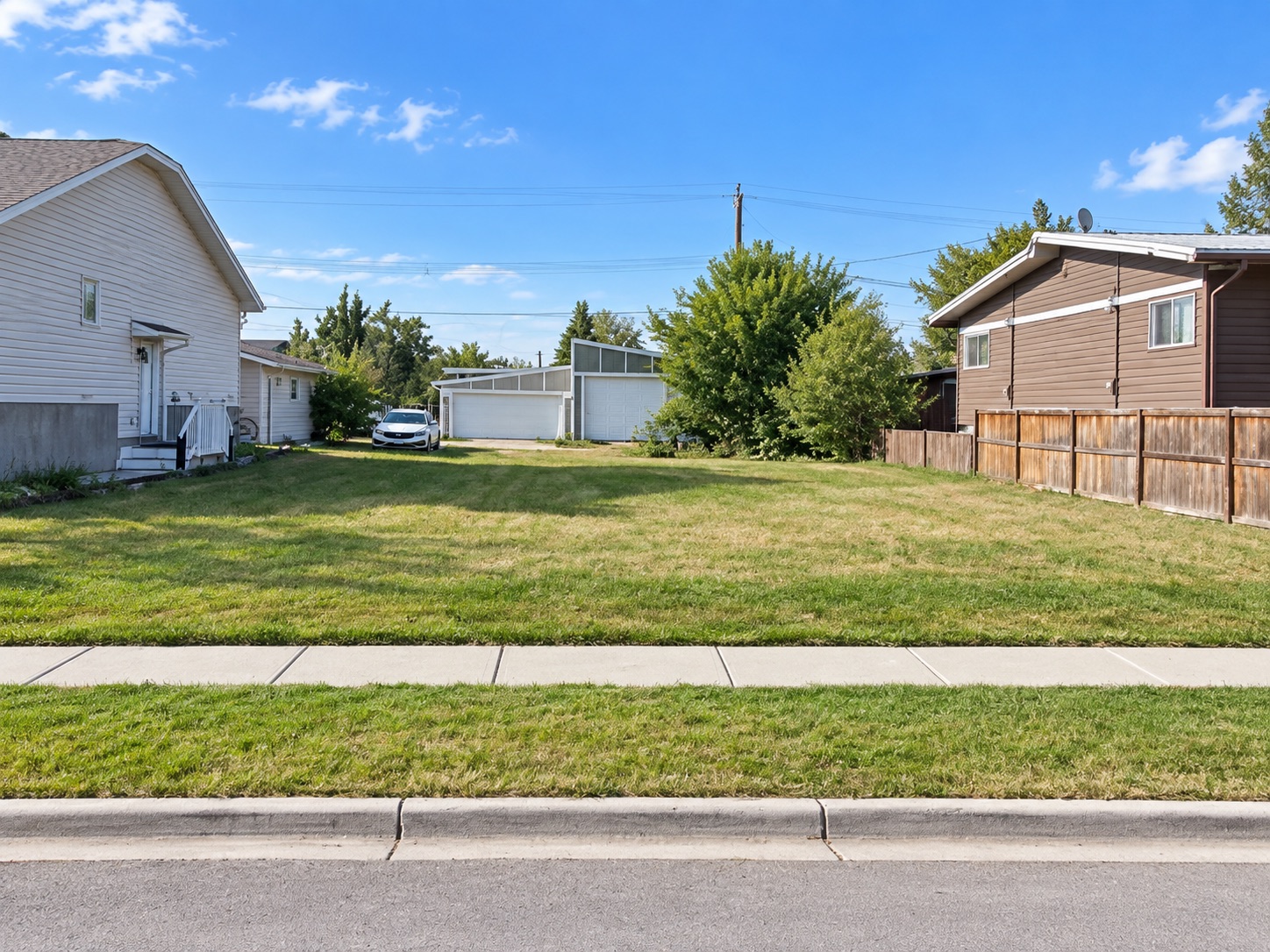 Wide street-level view across the vacant High River lot